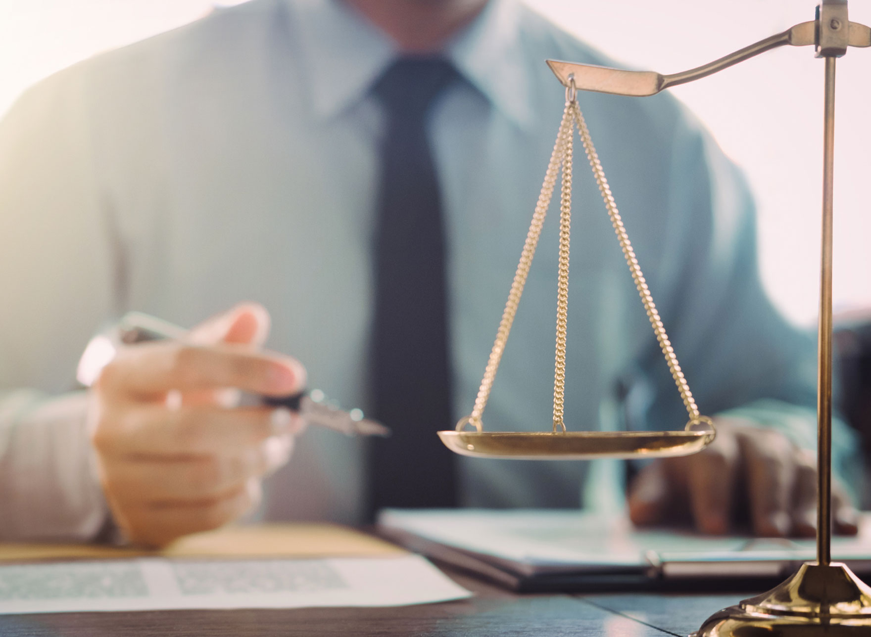 Law scales with person holding pen in background