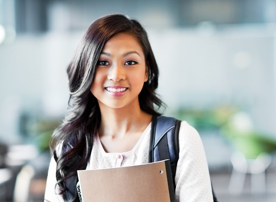 College student with backpack and notebook, smiling.