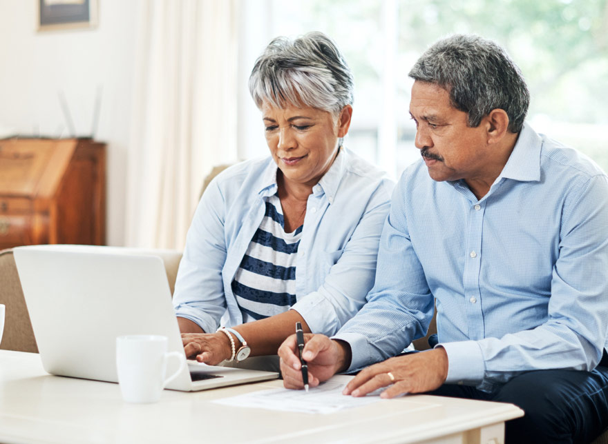 Husband and wife looking at their Sun Central Credit Union account on the computer together.